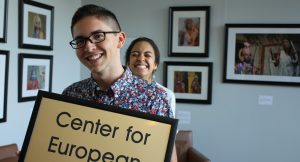 One student stands holding a sign that says Center for European Studies while another student smiles behind him in the Global Education Center.